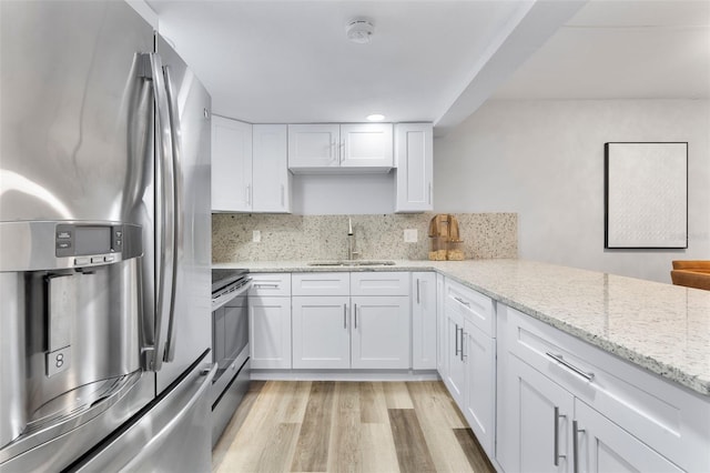 kitchen with stainless steel appliances, backsplash, white cabinets, light stone counters, and sink