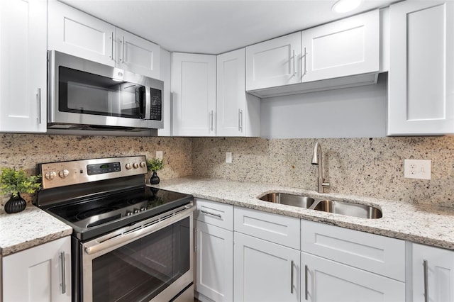 kitchen with backsplash, sink, white cabinetry, light stone countertops, and appliances with stainless steel finishes