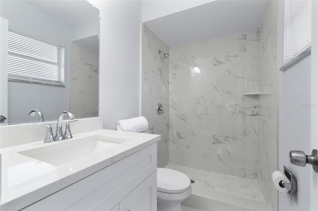 bathroom with toilet, vanity, and tiled shower