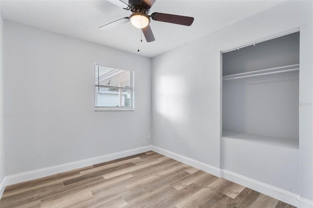 unfurnished bedroom featuring light wood-type flooring, ceiling fan, and a closet