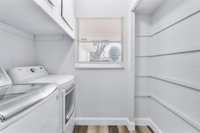 washroom featuring hardwood / wood-style flooring, cabinets, and washer and clothes dryer