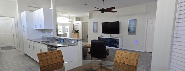 kitchen featuring sink, light hardwood / wood-style floors, hanging light fixtures, and white cabinets