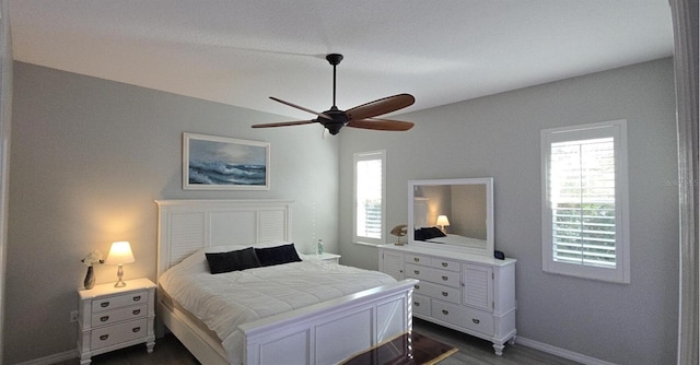 bedroom with ceiling fan, dark hardwood / wood-style flooring, and multiple windows