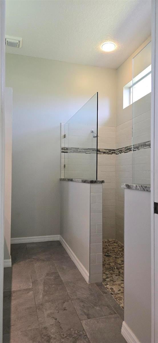 bathroom with a textured ceiling and a tile shower