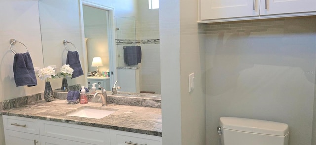 bathroom with vanity, tiled shower, and toilet