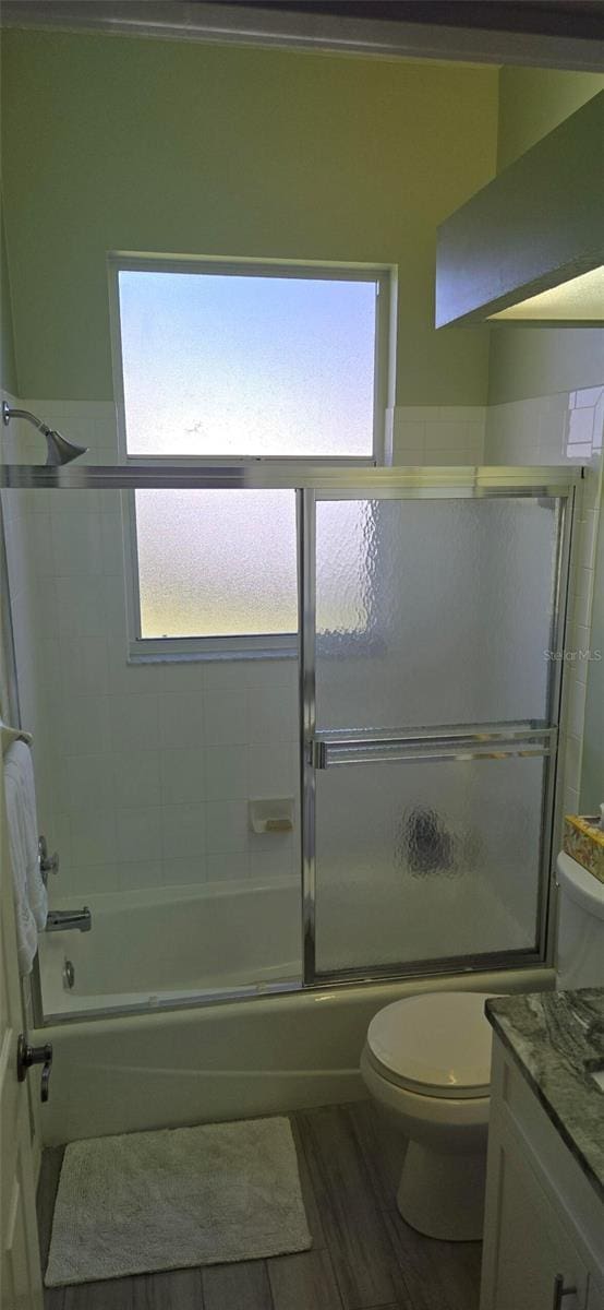 full bathroom featuring vanity, a healthy amount of sunlight, shower / bath combination with glass door, and toilet