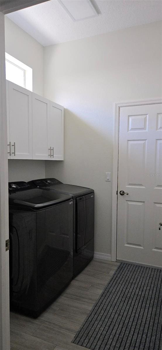 clothes washing area featuring cabinets, dark wood-type flooring, and washer and dryer