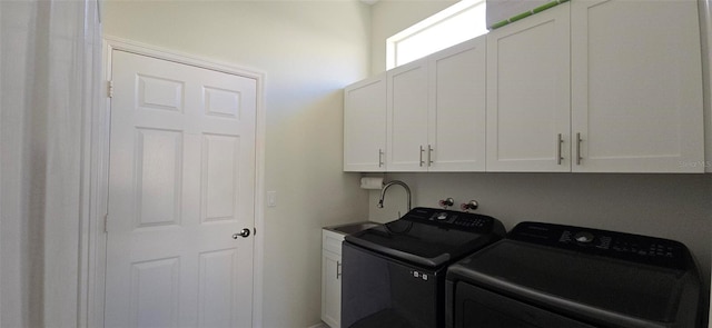 clothes washing area featuring cabinets, sink, and washer and dryer