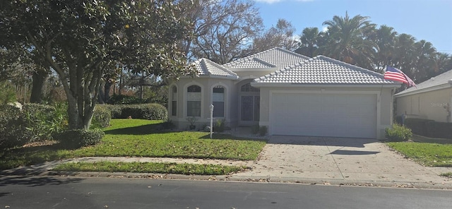 mediterranean / spanish home featuring a garage and a front lawn