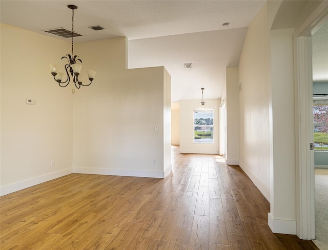 unfurnished room featuring a chandelier and light hardwood / wood-style floors