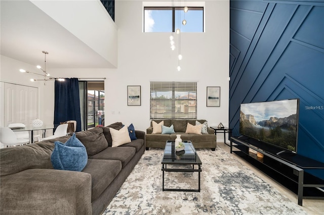 living room with a notable chandelier, plenty of natural light, and a towering ceiling