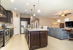 kitchen with pendant lighting, a center island with sink, stainless steel appliances, and dark brown cabinets