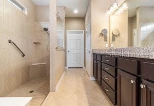 bathroom featuring tiled shower, vanity, and tile patterned flooring