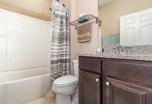 full bathroom with tile patterned flooring, vanity, toilet, and shower / tub combo with curtain