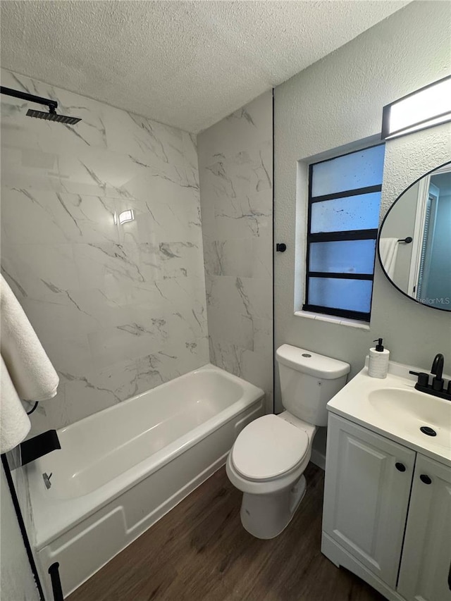 full bathroom with tiled shower / bath combo, hardwood / wood-style floors, a textured ceiling, toilet, and vanity