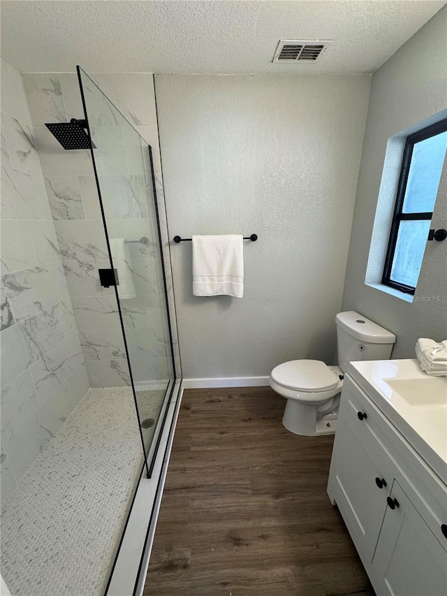 bathroom with wood-type flooring, vanity, a textured ceiling, and a tile shower