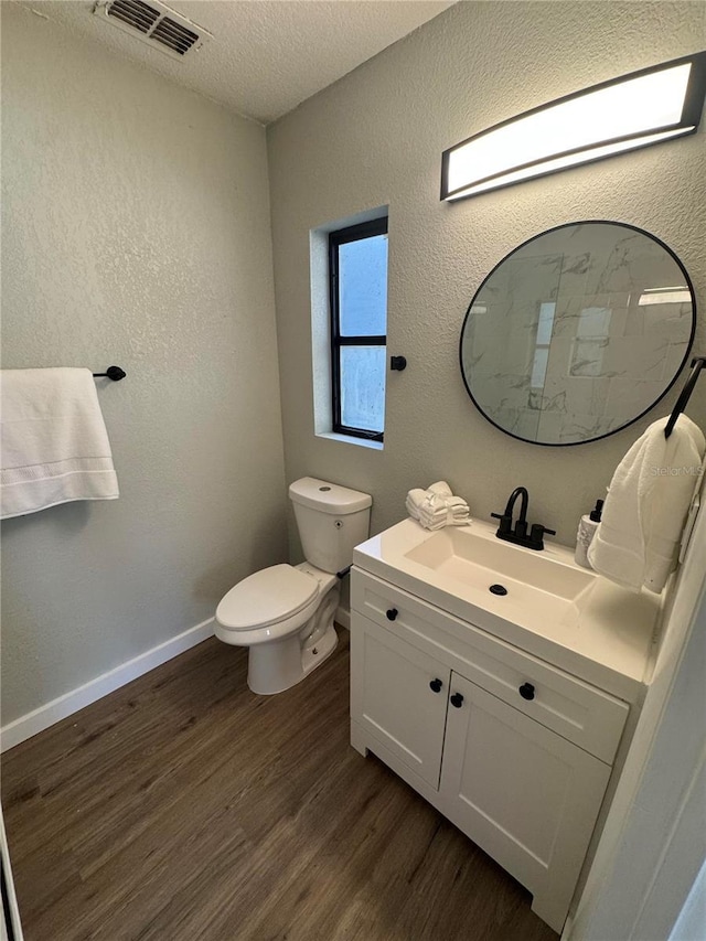 bathroom with toilet, vanity, a textured ceiling, and hardwood / wood-style flooring