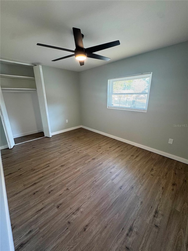 unfurnished bedroom featuring ceiling fan, dark wood-type flooring, and a closet