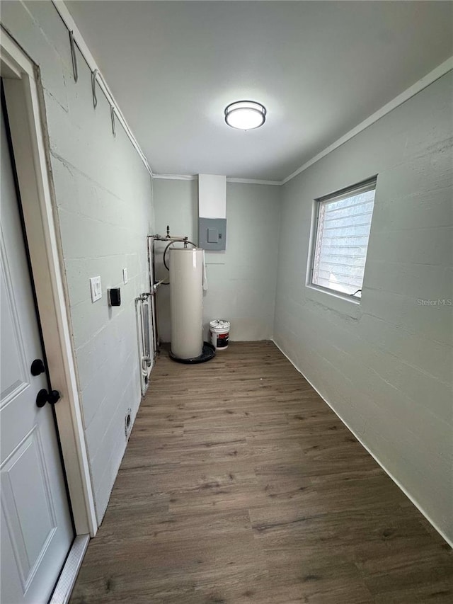 clothes washing area featuring wood-type flooring, electric panel, crown molding, and water heater