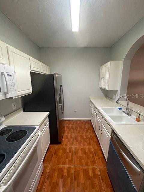 kitchen with sink, white cabinets, and white appliances