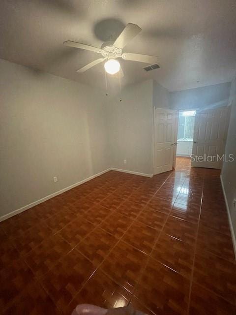 spare room featuring dark tile patterned floors and ceiling fan