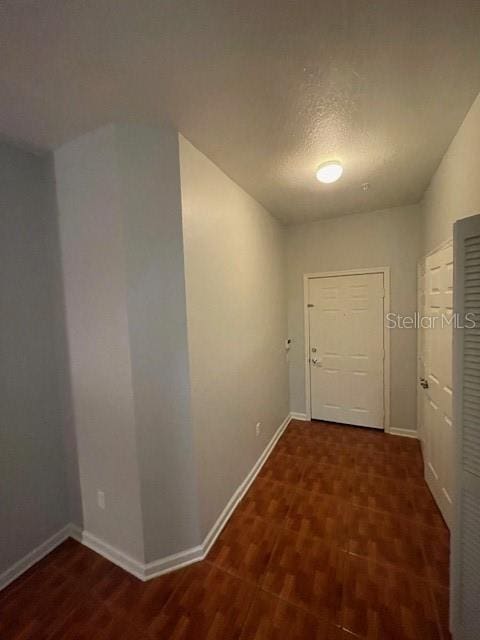 corridor with a textured ceiling and dark hardwood / wood-style flooring