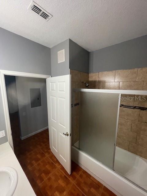 bathroom with vanity, combined bath / shower with glass door, hardwood / wood-style floors, and a textured ceiling