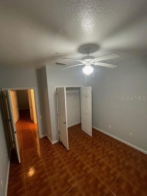 unfurnished bedroom with ceiling fan, a closet, and a textured ceiling