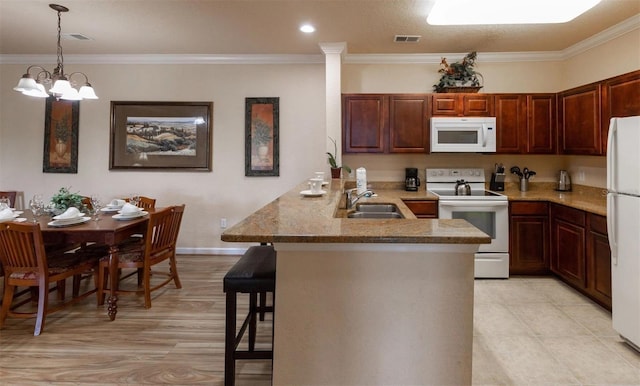 kitchen with kitchen peninsula, a kitchen breakfast bar, white appliances, crown molding, and an inviting chandelier