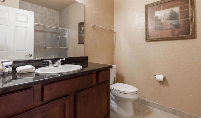 bathroom with tile patterned floors, a shower with door, vanity, and toilet