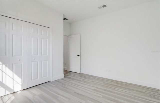 unfurnished bedroom with light wood-type flooring and a closet