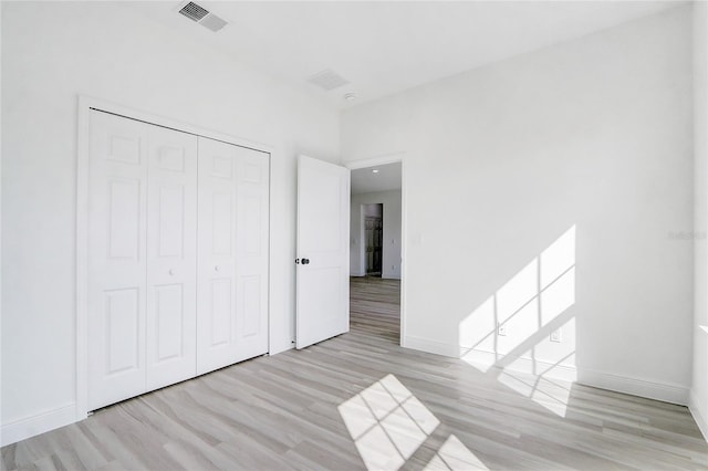 unfurnished bedroom featuring light wood-type flooring and a closet