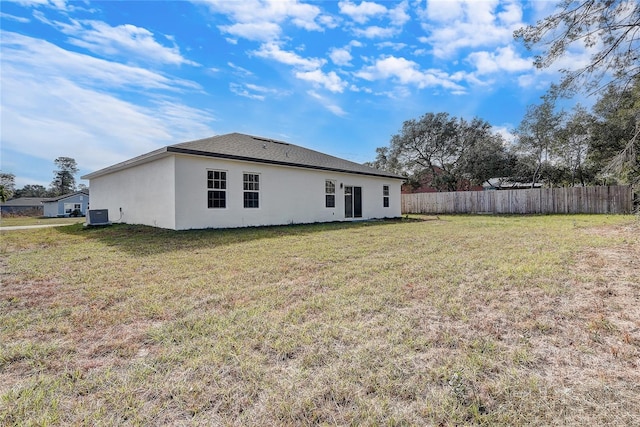 back of house with central AC unit and a lawn