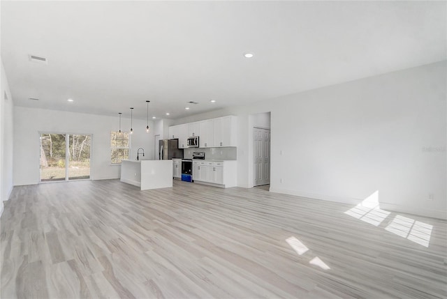 unfurnished living room featuring sink and light hardwood / wood-style floors