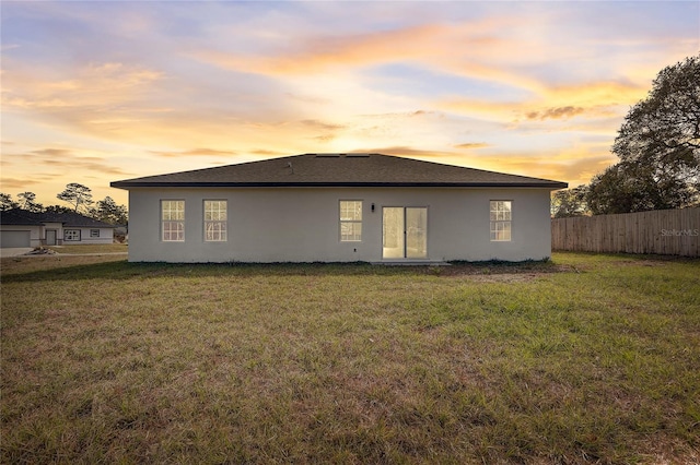 back house at dusk featuring a yard