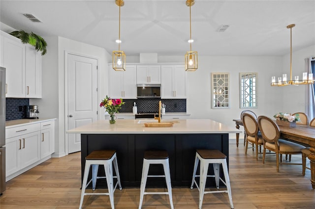 kitchen featuring sink, white cabinetry, and a kitchen island with sink