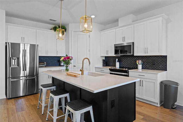 kitchen with sink, white cabinetry, stainless steel appliances, and a kitchen island with sink