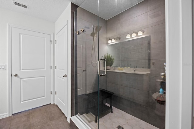 bathroom with tile patterned flooring, a textured ceiling, and an enclosed shower