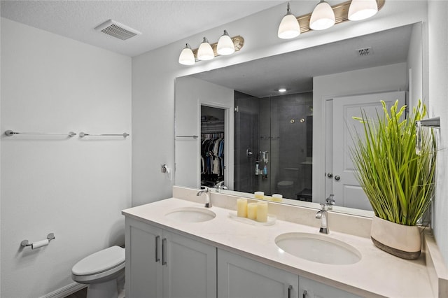 bathroom featuring a textured ceiling, vanity, an enclosed shower, and toilet