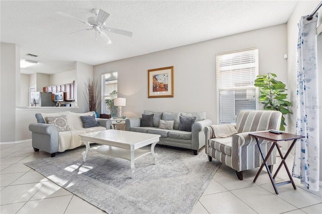 living room with a textured ceiling, ceiling fan, and light tile patterned flooring