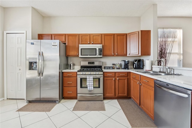 kitchen with a textured ceiling, light tile patterned flooring, sink, and appliances with stainless steel finishes