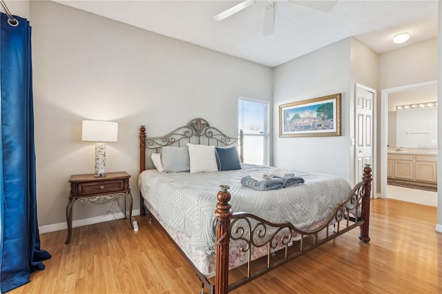 bedroom featuring ceiling fan, sink, light hardwood / wood-style flooring, ensuite bathroom, and a textured ceiling