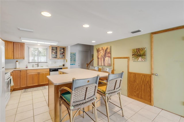 kitchen featuring decorative backsplash, sink, light tile patterned floors, dishwasher, and a center island