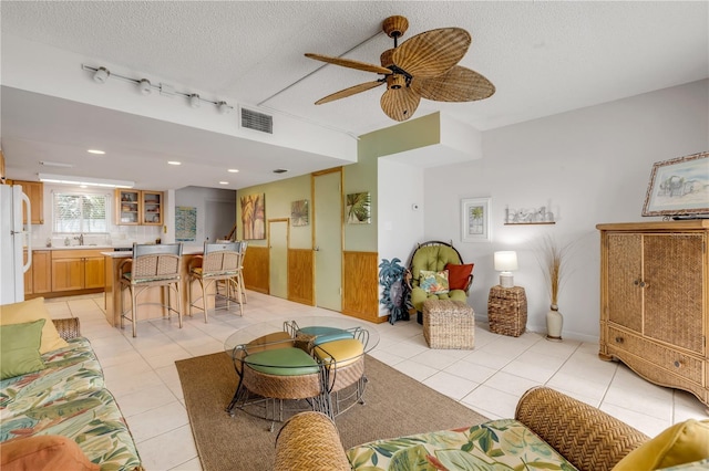 tiled living room featuring ceiling fan, sink, and a textured ceiling