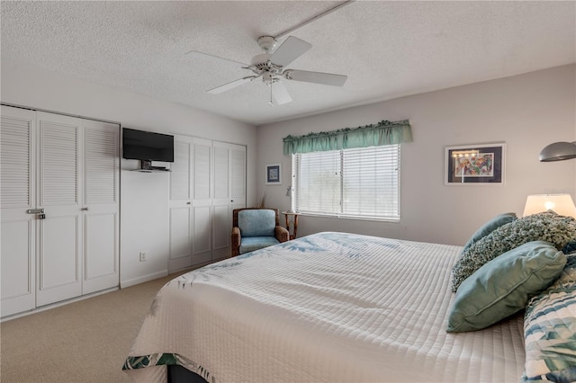 bedroom featuring ceiling fan, a textured ceiling, and two closets