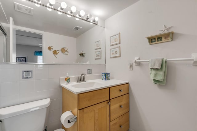 bathroom featuring vanity, toilet, and tile walls