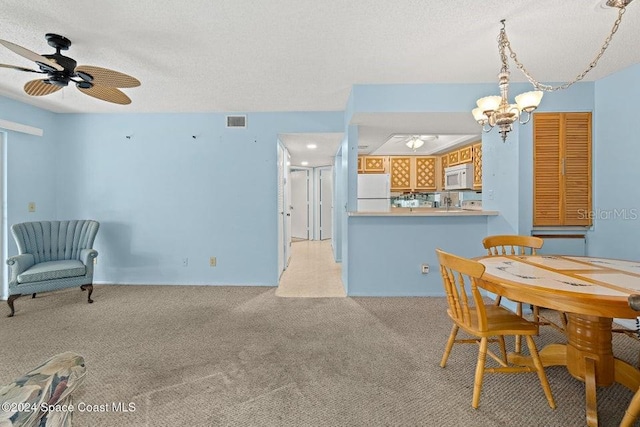 dining area with a textured ceiling, light colored carpet, and ceiling fan with notable chandelier