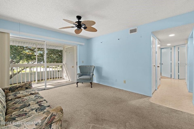 living area featuring ceiling fan, plenty of natural light, light colored carpet, and a textured ceiling