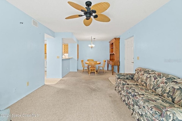 carpeted living room with ceiling fan with notable chandelier