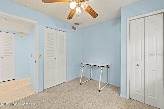 misc room featuring ceiling fan, light colored carpet, and a textured ceiling